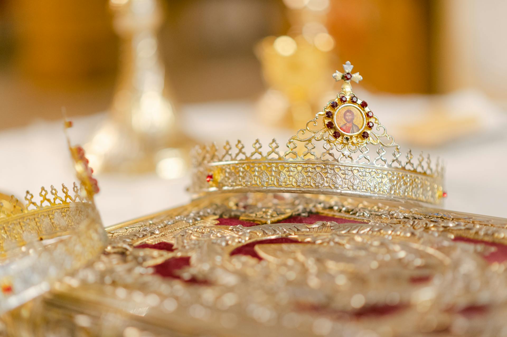 Close-up of a luxurious gold crown adorned with intricate designs and jewels, symbolizing royalty and opulence.