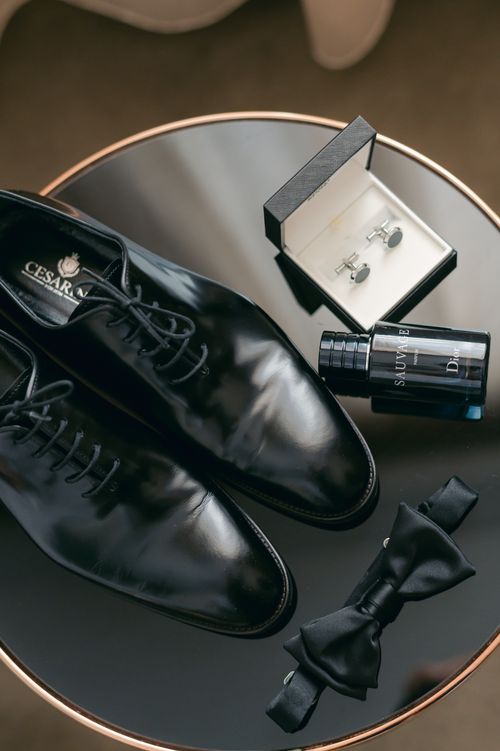 Free Black Oxfords, bowtie, cufflinks, and fragrance displayed on a reflective surface. Stock Photo