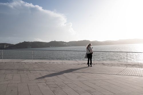 Woman Standing on Pavement on Sea Coast at Sunset