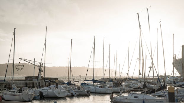 A serene view of sailboats docked at a marina in Lisbon, Portugal at sunset.
