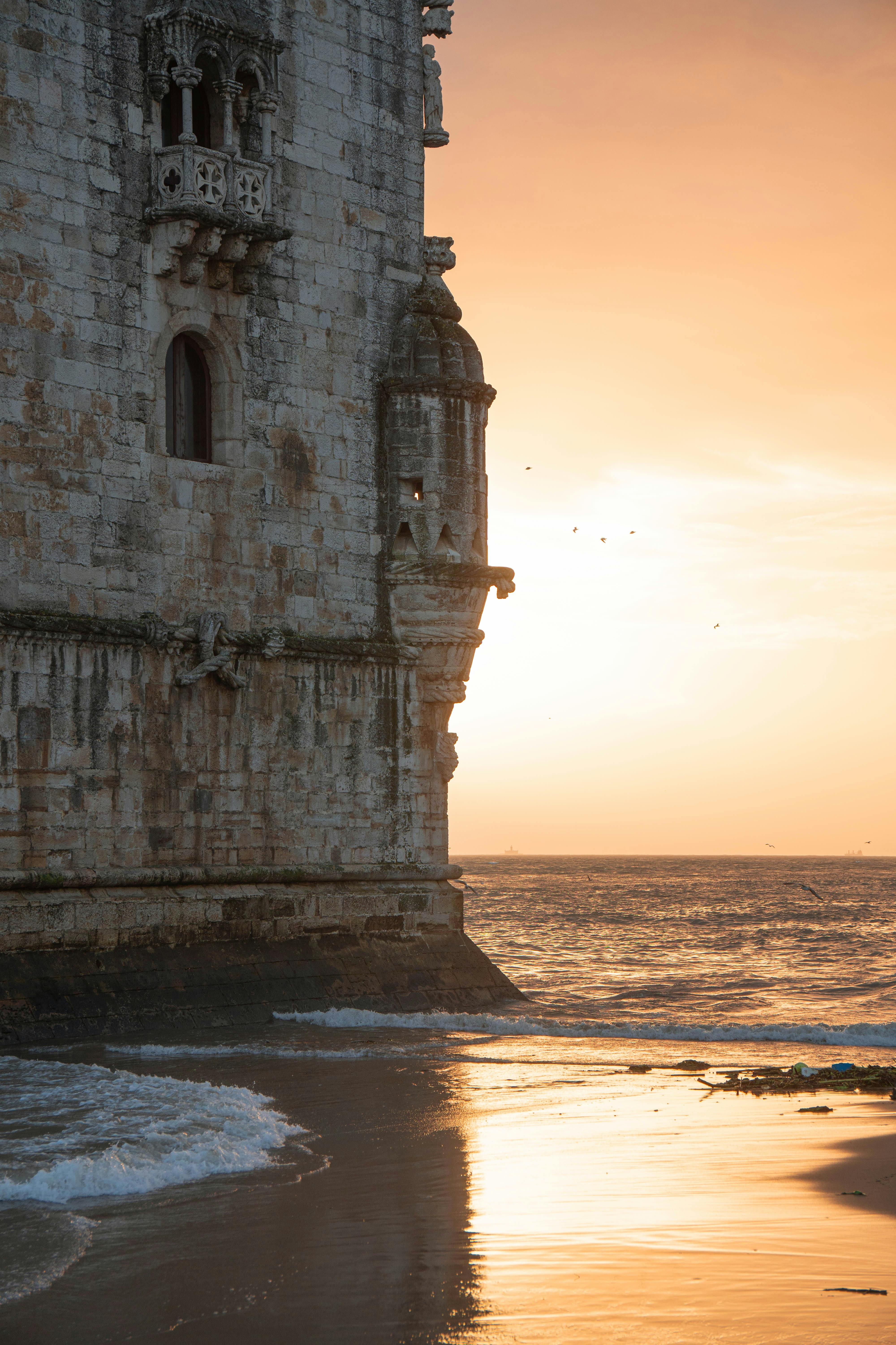 Beautiful sunset view of the Belem Tower by the seashore in Lisbon, highlighting its architectural charm.