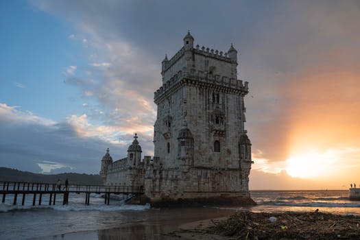 Stunning view of Belem Tower in Lisbon glowing in the sunset by the riverbank.
