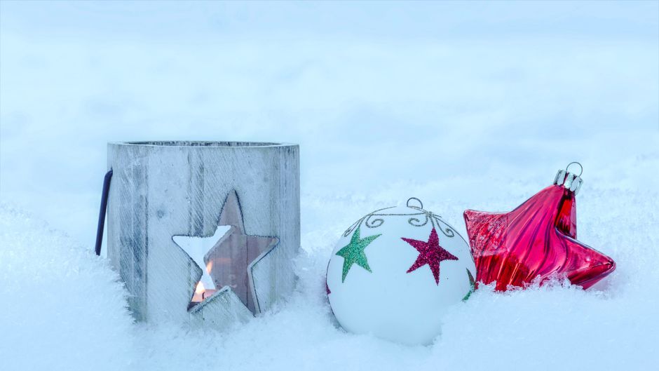 冬の雪の中のキャンドルホルダーとオーナメントを使った心地よいクリスマスシーン。