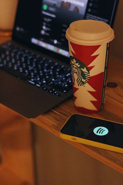 Free Starbucks Coffee Beside the Laptop on the Table Stock Photo