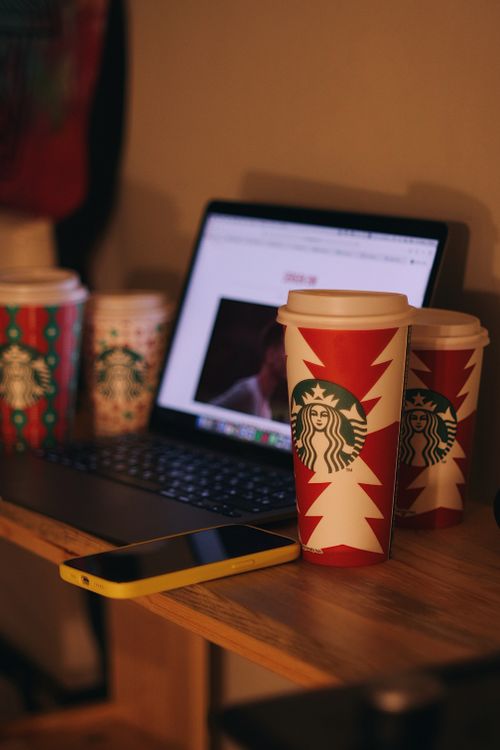 Free A warm indoor workspace featuring a laptop and festive Starbucks cups. Stock Photo