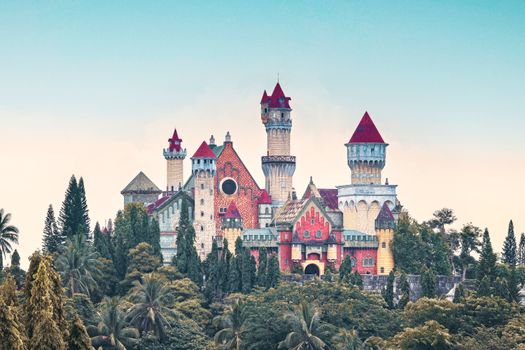 A colorful fairytale castle surrounded by lush trees under a clear blue sky.