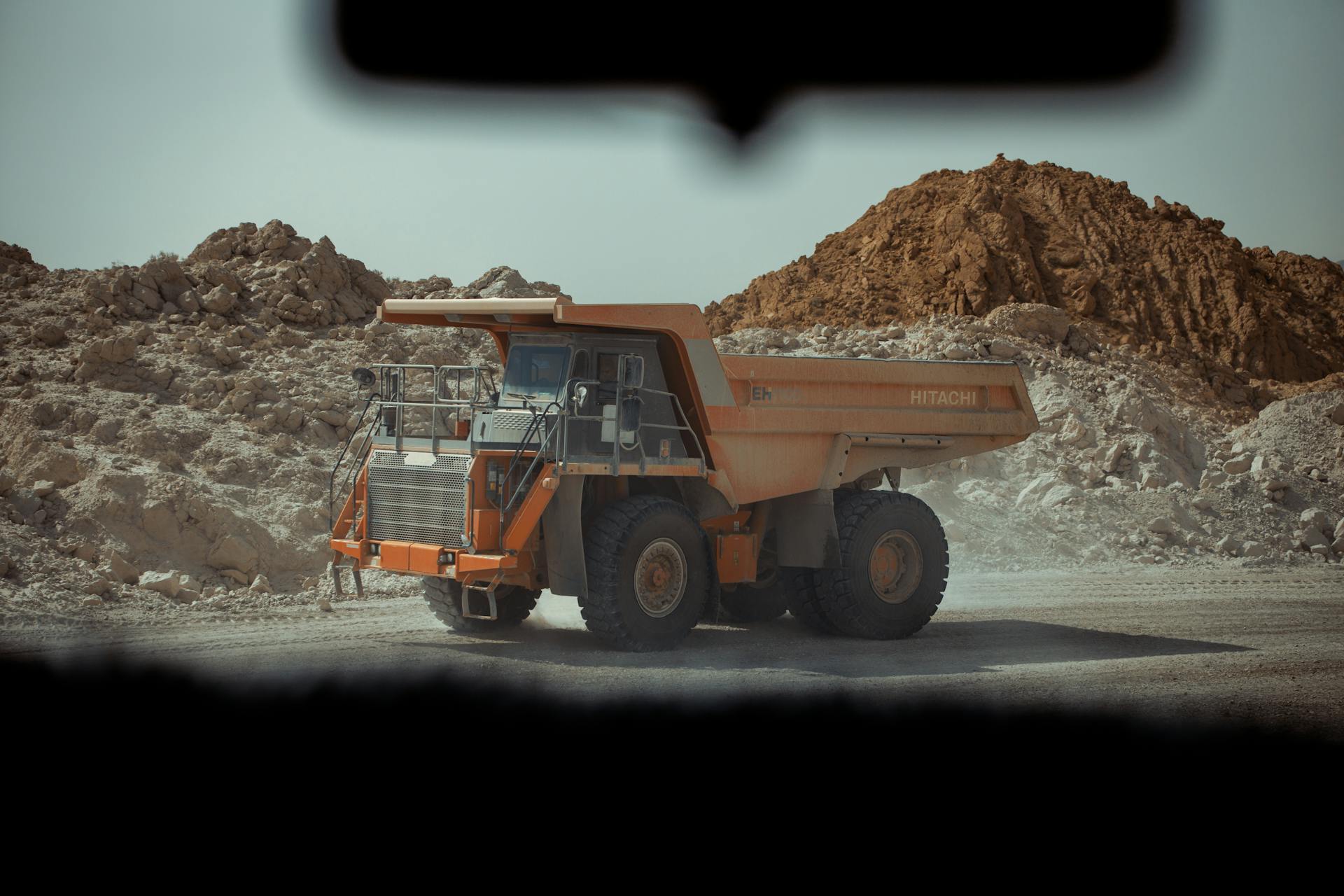 A large dump truck operates in a dusty quarry in Biskra, Algeria.