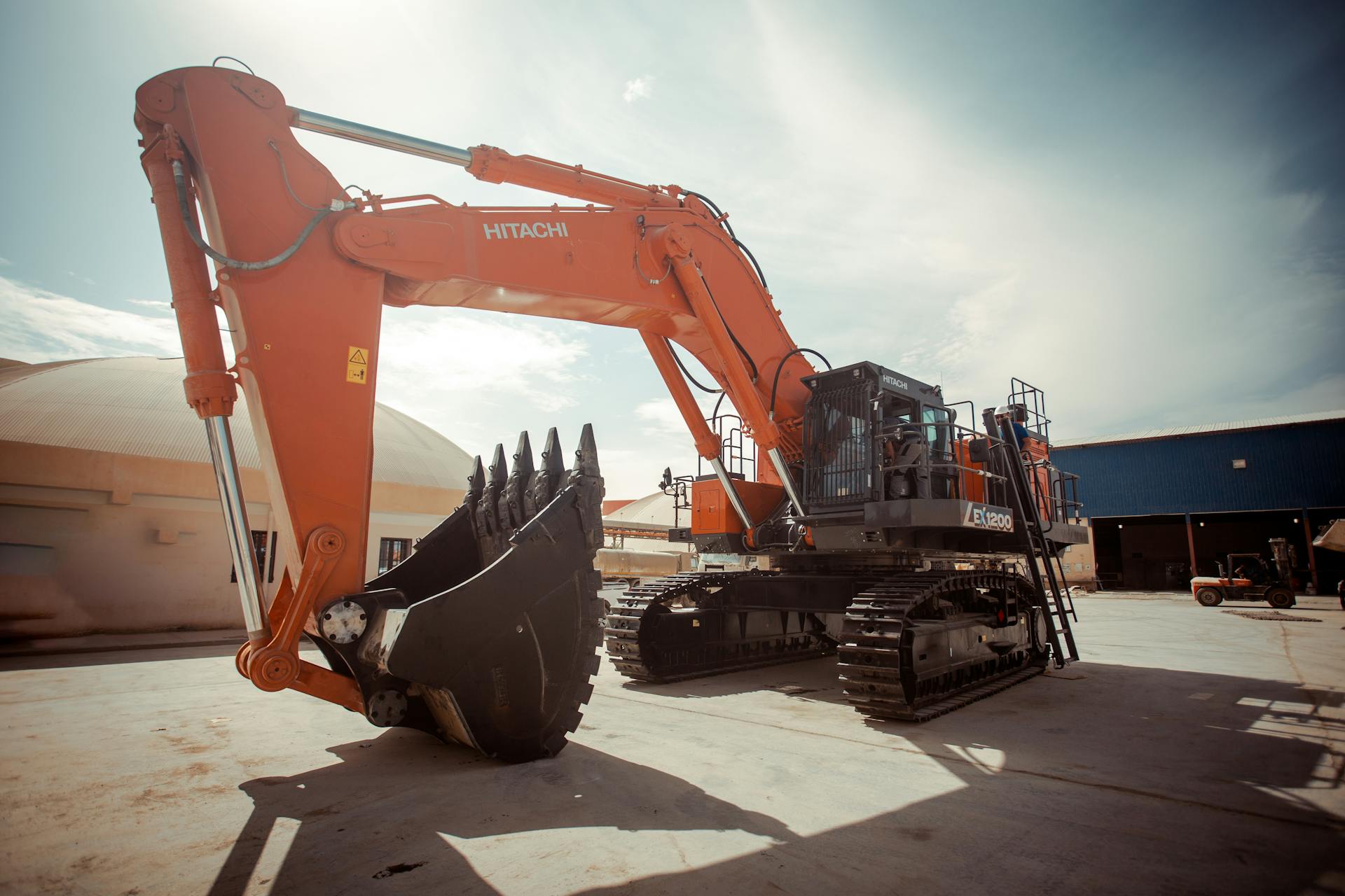 Large Hitachi excavator on a construction site in Biskra, Algeria, under bright daylight.