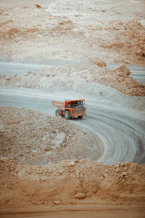 Free A heavy dump truck navigates a winding dirt road through the barren desert landscape of Biskra, Algeria. Stock Photo