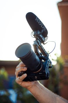 Cinematic setup showing a camera with a Rode microphone in a hand, perfect for videography.