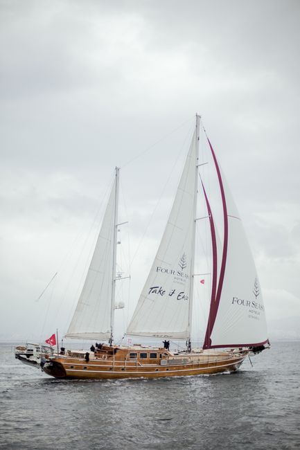 A luxurious sailboat cruising on the serene waters of Istanbul with cloudy skies above.