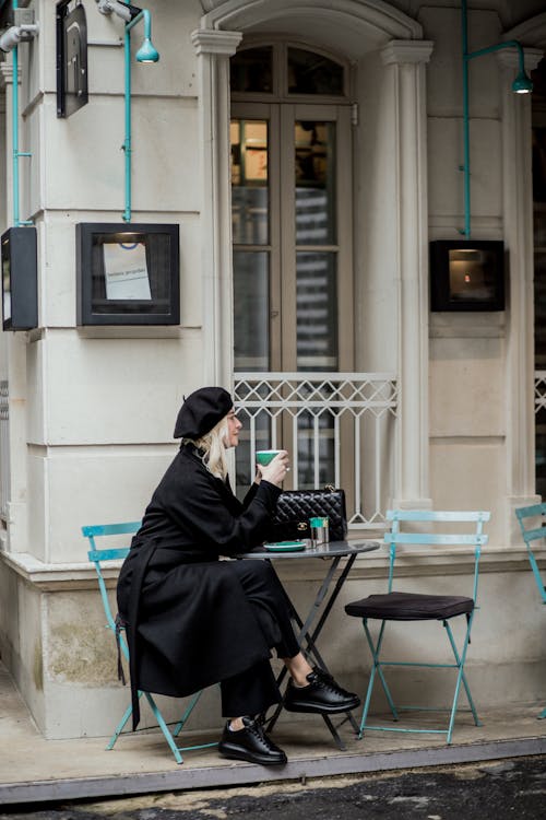 Woman in Black Coat Sitting at Cafe on Street in Town · Free Stock Photo