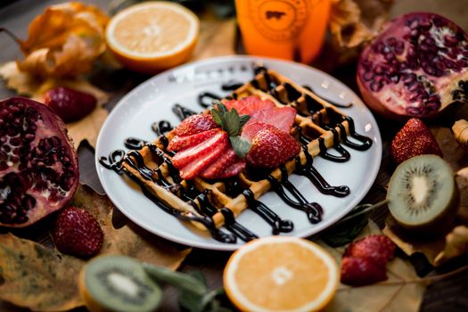 A vibrant still life of a waffle topped with strawberries surrounded by assorted fresh fruits.