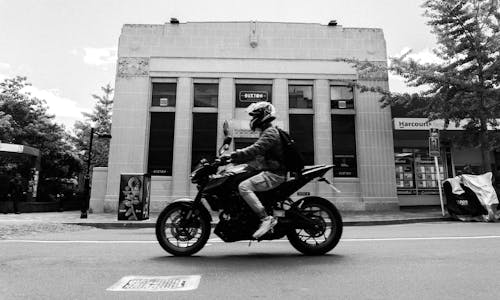 Grayscale Photo of a Man Riding Motorcycle on the Street