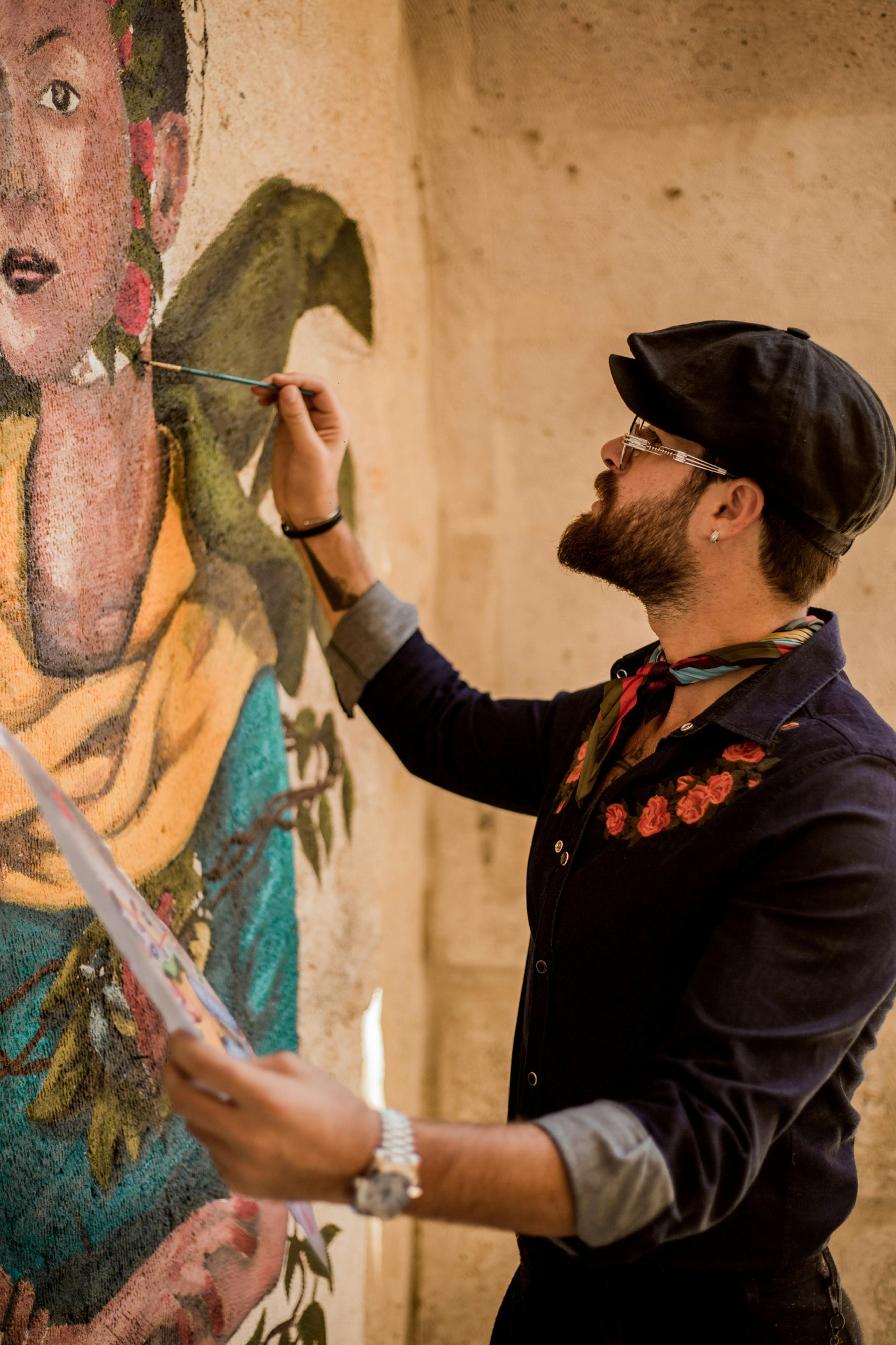 a man in a hat and shirt is painting a mural