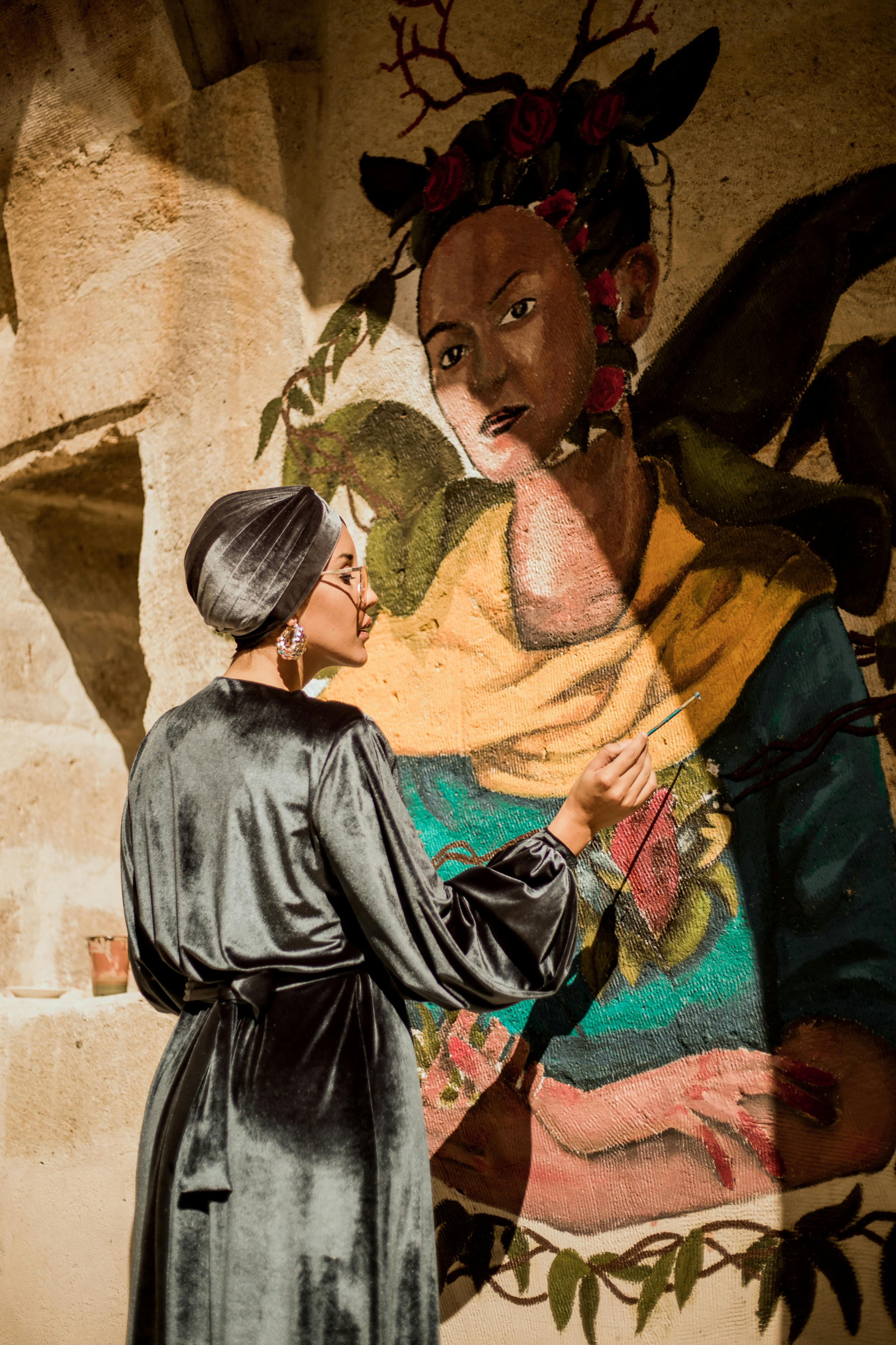 a woman in a robe painting a mural