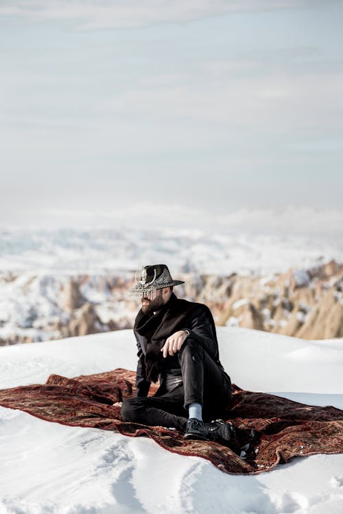 Model in Black Clothes Sitting on Blanket on Snow