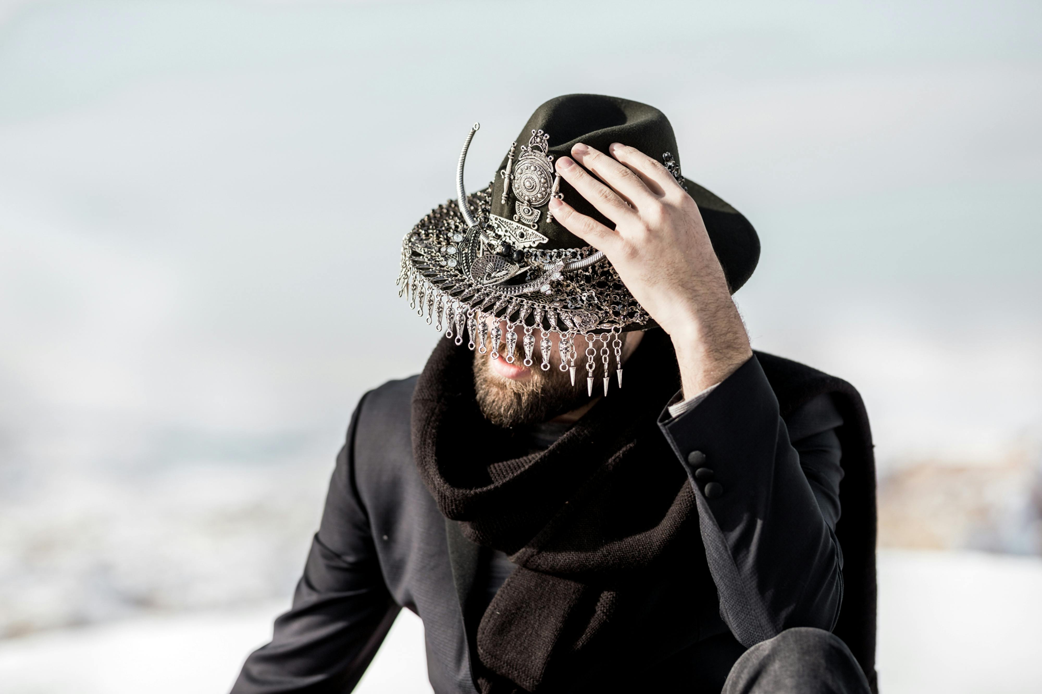 Stylish portrait of man in Ortahisar, wearing a black coat and ornamented hat.