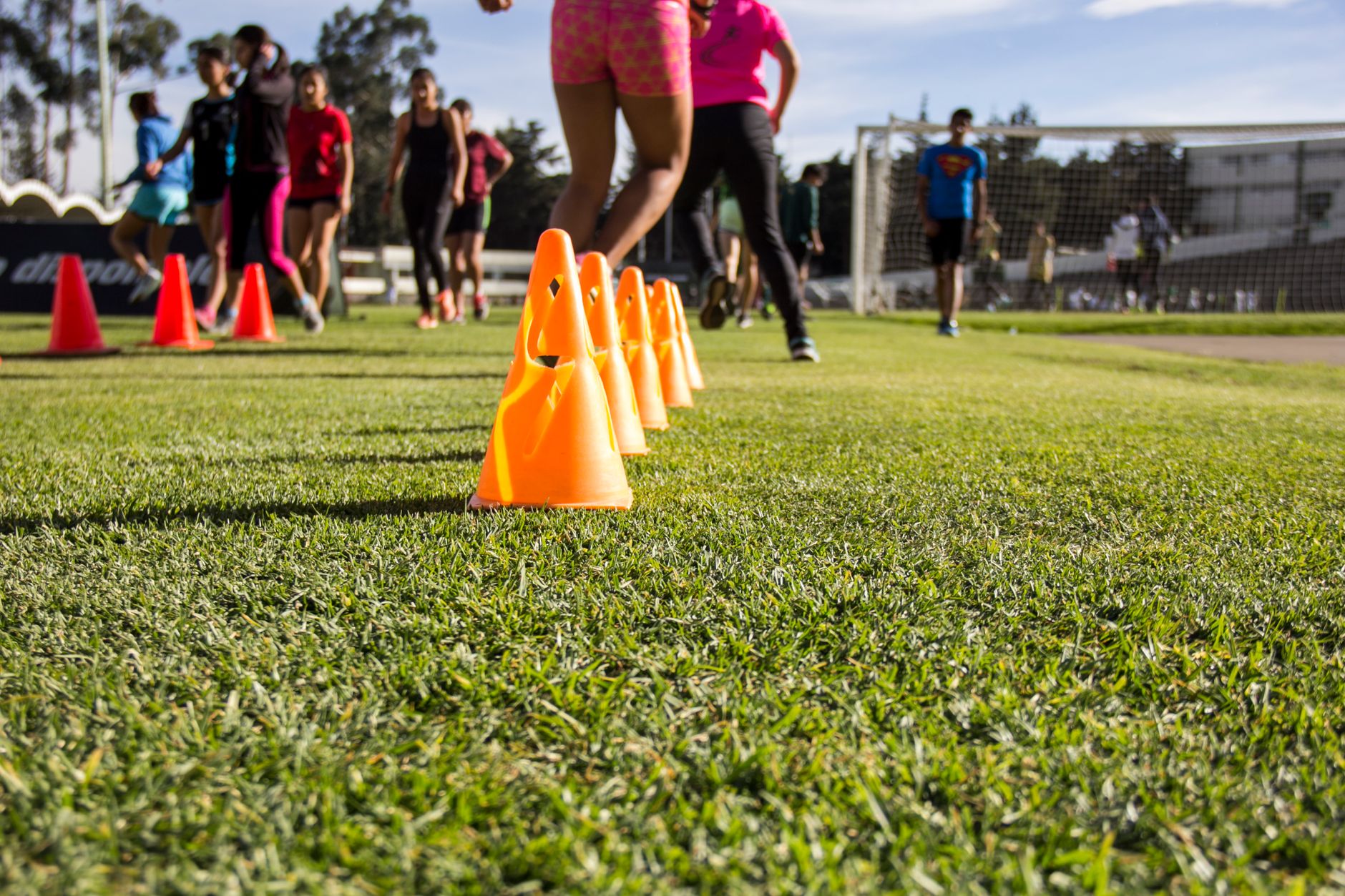 football cones, stopwatch, resistance bands, and water bottle arranged beside a marked training grid