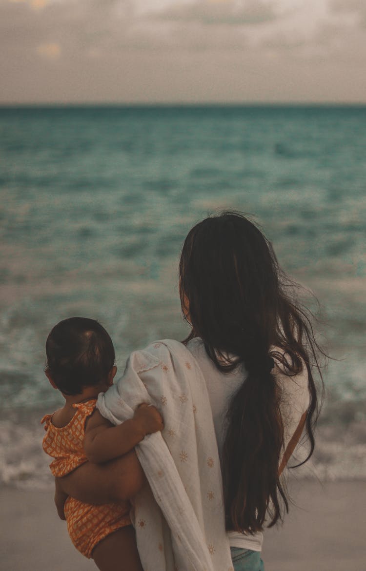 A Parent Holding Their Child By The Seaside