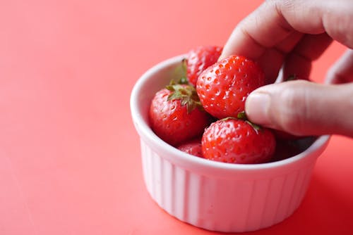 Close-up of a Person Taking a Strawberry from a Bowl 