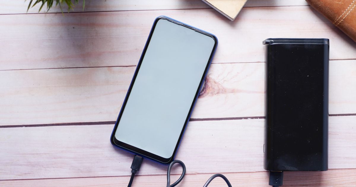 A phone charging from a power bank on a wooden table