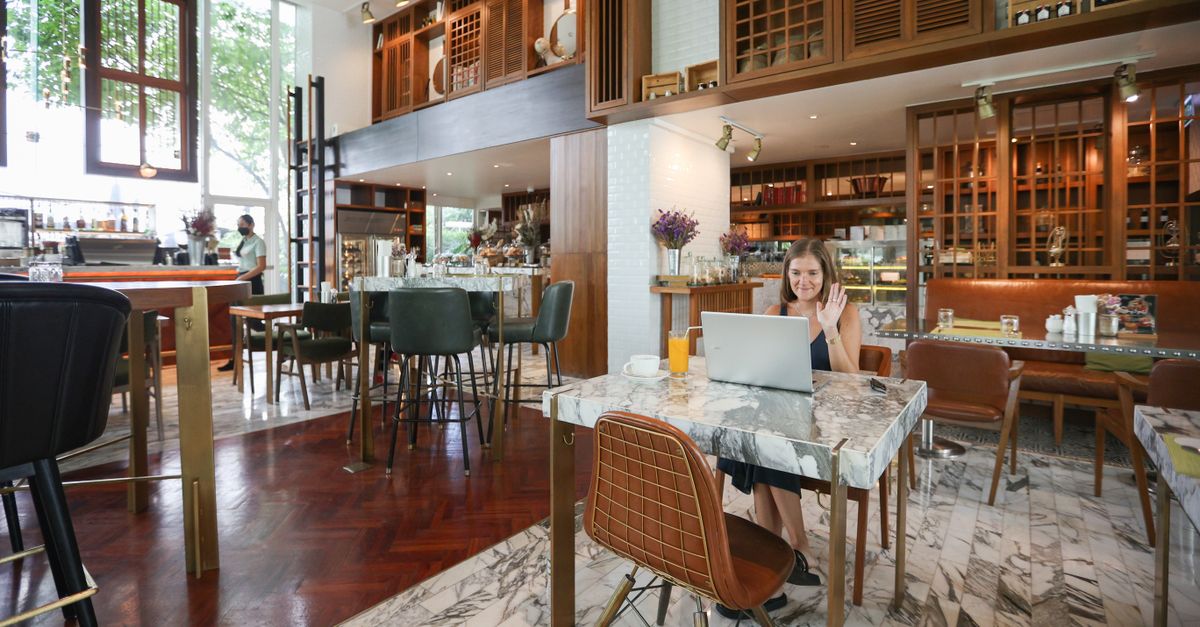 Woman working on a laptop in an open, airy cafe setting with natural light.