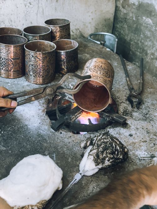 Free Artisan heats metal container using open flame in rustic workshop. Craftsmanship and metal arts. Stock Photo