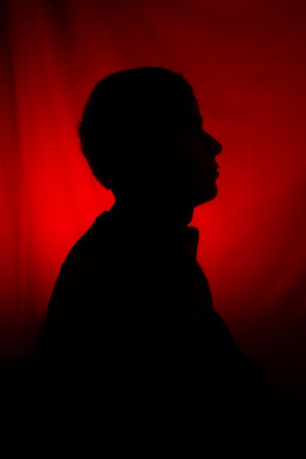 Artistic silhouette of a person against a striking red backdrop, conveying mystery and drama.