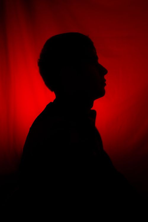 Free Artistic silhouette of a person against a striking red backdrop, conveying mystery and drama. Stock Photo