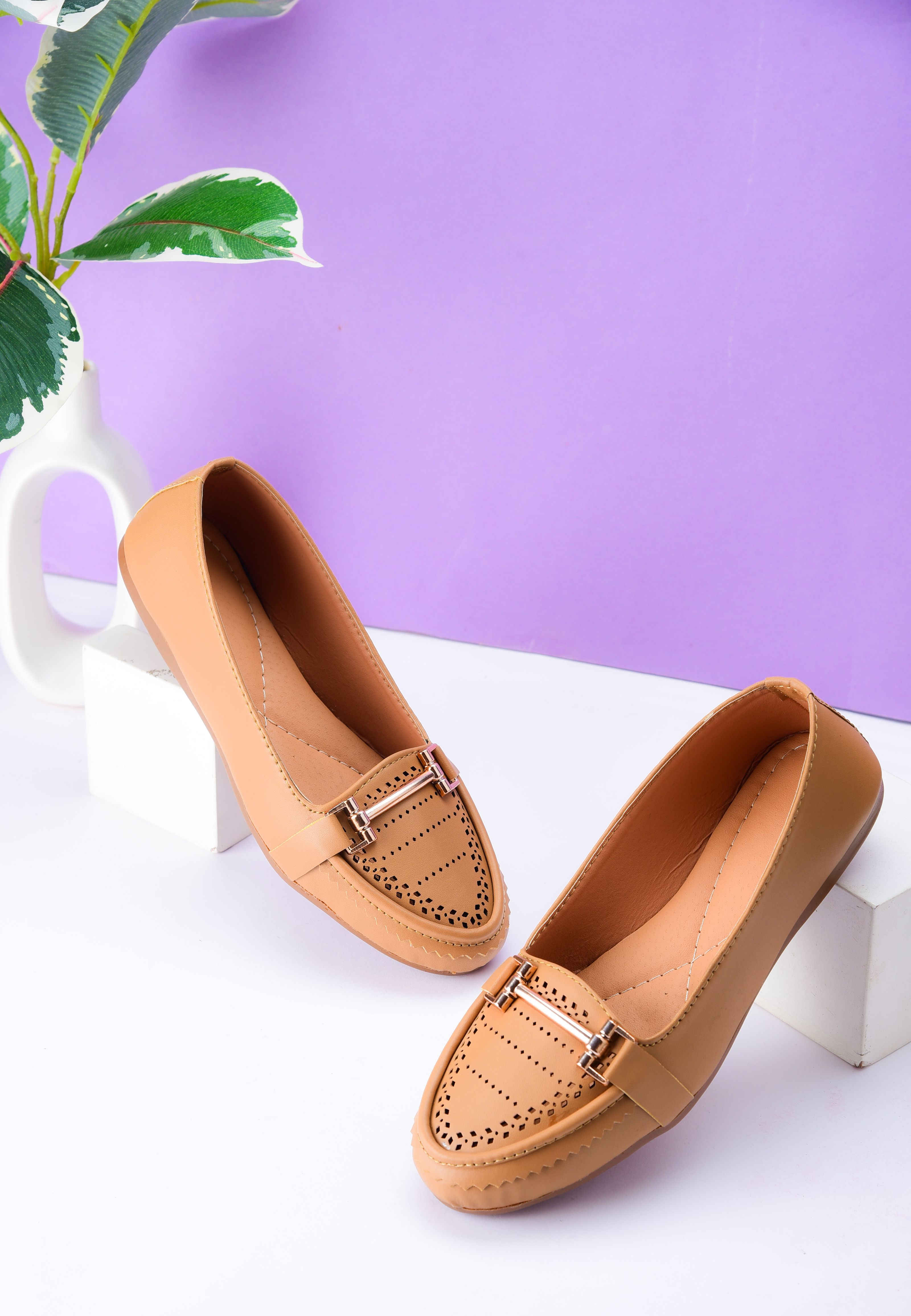 Mocassins marrons fashion exibidos contra um fundo roxo vibrante.