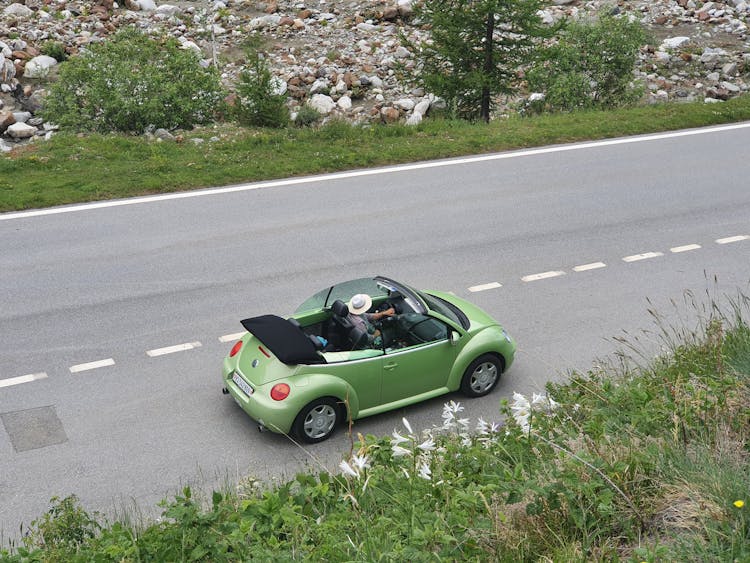 A Person Driving A Green Top Down Car On The Road