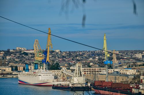 Free A busy harbor featuring ships and cranes in an urban setting. Stock Photo