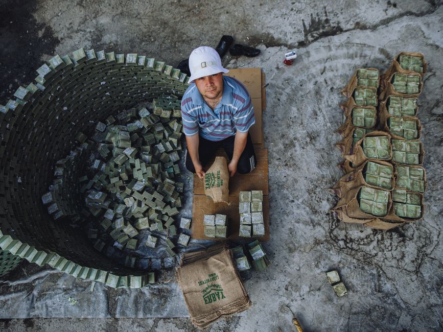 High-angle view of a worker arranging green bricks in an industrial environment.