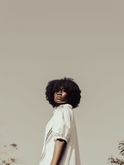 Free A stylish young woman in a white dress posing confidently outdoors in summer. Stock Photo