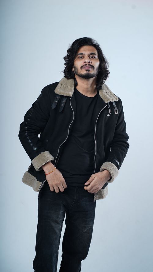 Free Confident man with long hair in black jacket posing against white background. Stock Photo