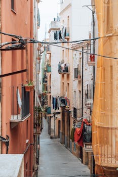 Explore a vibrant alleyway lined with colorful buildings and hanging laundry, capturing the essence of city life.
