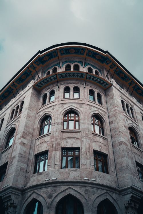 Free Low angle view of a historic building with elegant arched windows and ornate detailing against a cloudy sky. Stock Photo