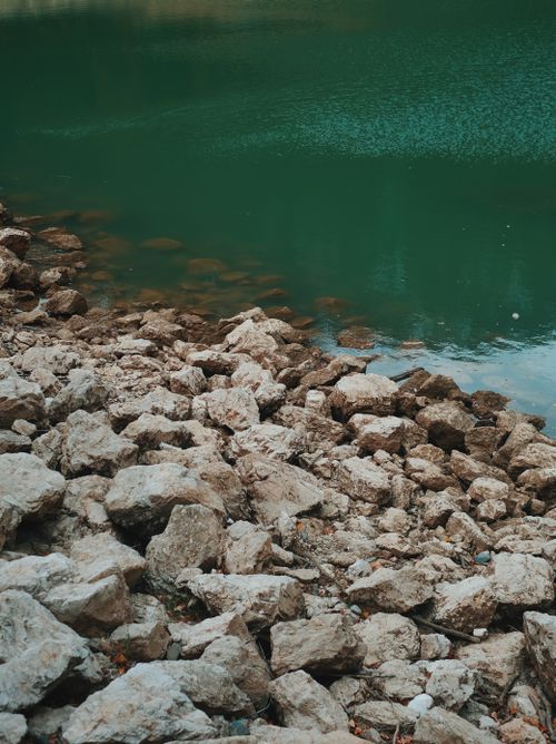 Free A peaceful turquoise lake surrounded by a rocky shoreline, perfect for nature enthusiasts. Stock Photo