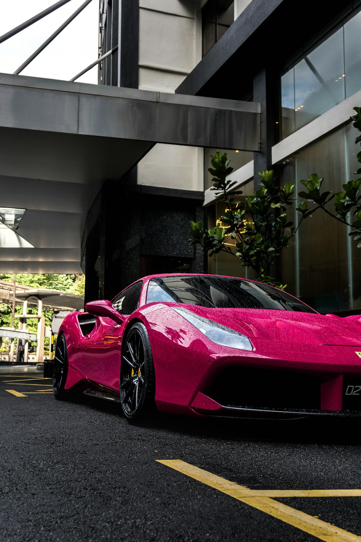 Auto sportiva rossa parcheggiata davanti all'ingresso di un hotel di lusso
