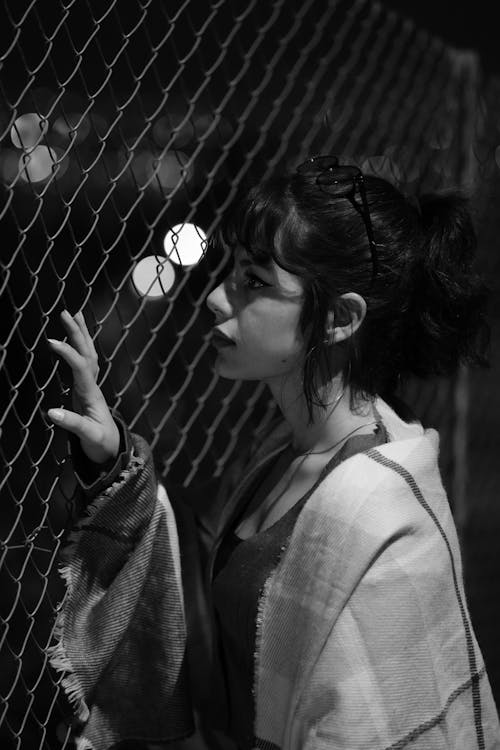 Woman Holding on Chain Link Fence