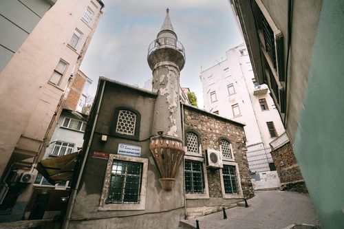 Free A low-angle view of a historic Ottoman mosque surrounded by urban buildings. Stock Photo