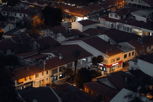 Aerial view of illuminated town rooftops at dusk showcasing urban architecture.