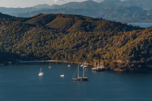 Free A scenic aerial view of a tranquil cove with sailboats surrounded by lush green mountains. Stock Photo