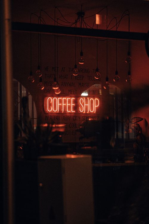 Free Warm and inviting coffee shop with neon signage, creating a cozy urban atmosphere. Stock Photo