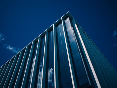 Low-angle view of a modern glass building facade against a clear blue sky.