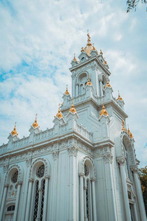 Free A beautiful neo-gothic church with ornate architecture and gold accents under a blue sky. Stock Photo