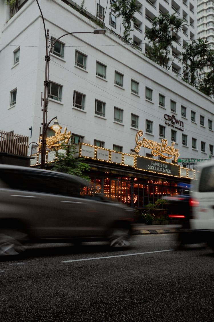 Cars Driving On Road Near Restaurant Building