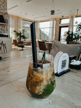 Close-up of a fresh cocktail with straw on a table in a cozy indoor café setting in Khor Fakkan.