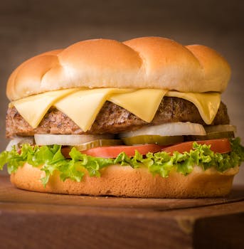 Close-up of a delicious cheeseburger with fresh toppings on a wooden surface.